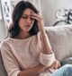 woman sitting on the couch holding her head due to fatigue after quitting alcohol