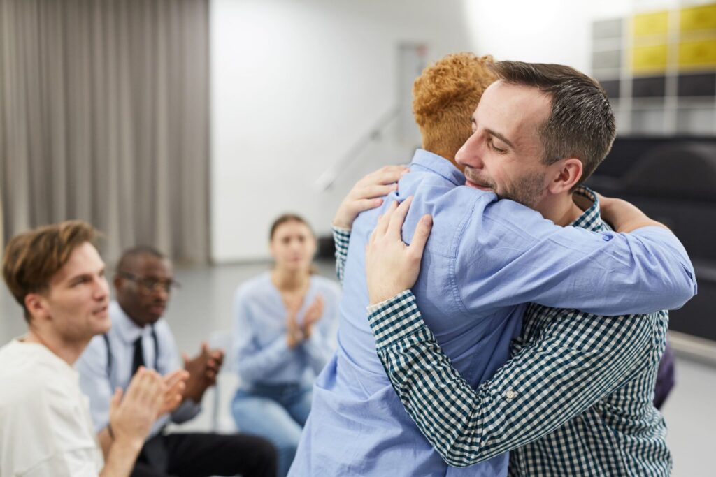 Men hugging in group therapy in Massachusetts.