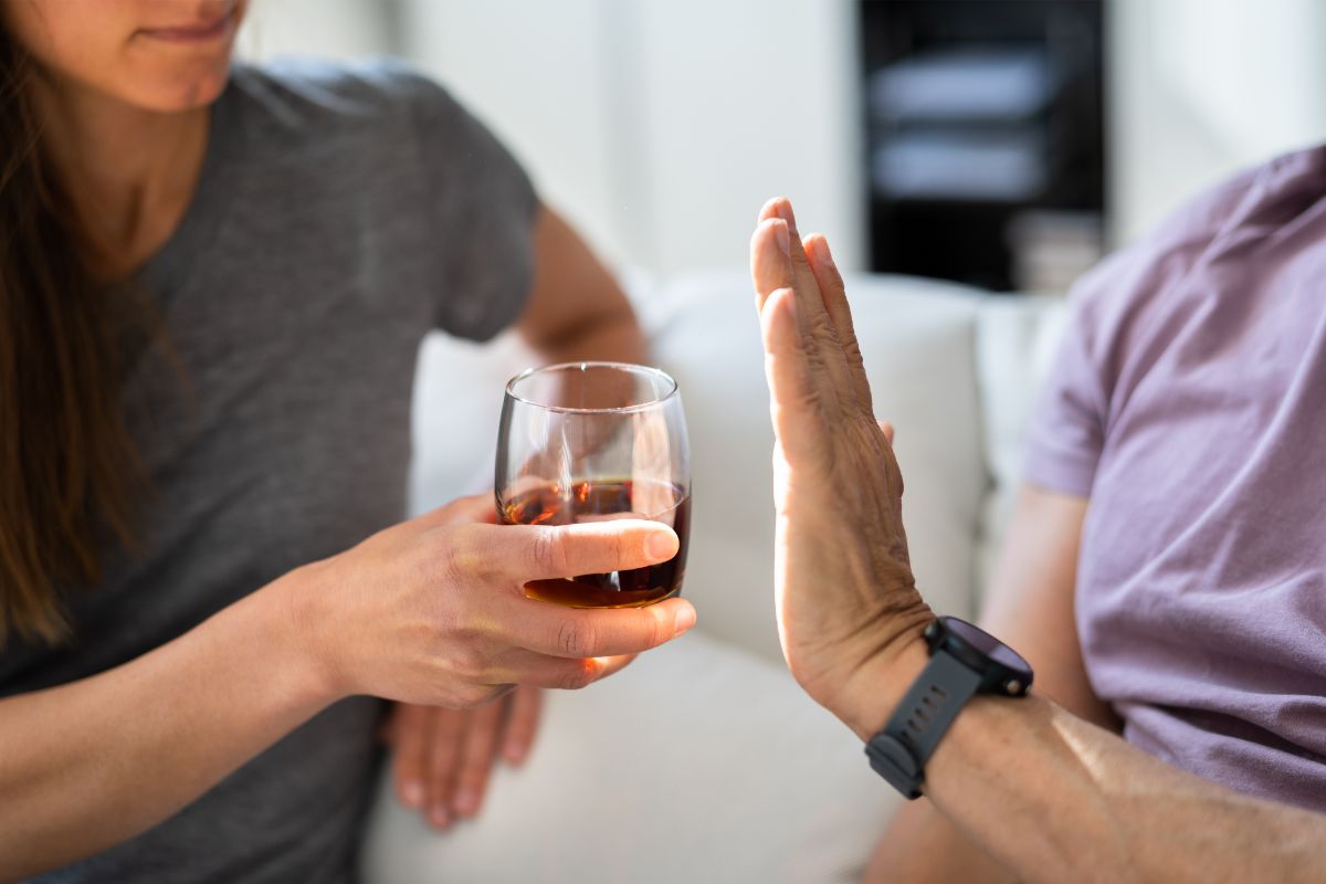 person putting their hand up to refuse a drink after quitting alcohol